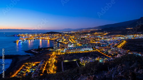 Spain  Tenerife  Lost christianos tourist resort city skyline in magical illuminated atmosphere after sunset  aerial view above