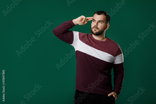 portrait of bearded man thinking and asking questions on green background. copy space