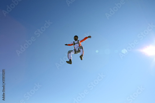 Up. Fly men is a pilot of his body in air. Extreme people prefer skydiving. Parachutist in white and orange suit. Free lifestyle.