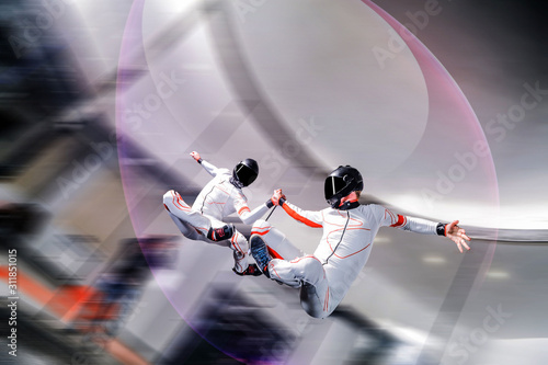 Up. Extreme people prefere sky sport. Fly men perfoms trick in air. Parachutist in white and orange suit is in free fall. Skydiving is sport without rules.