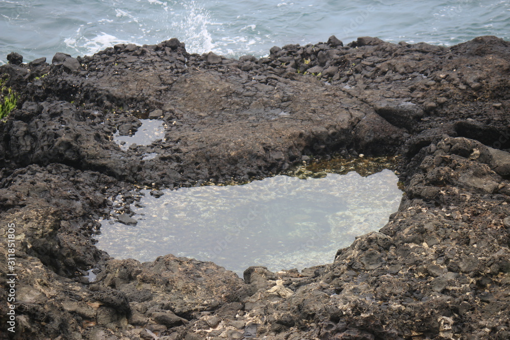 a puddle of water in the middle of a rock in the middle of the sea