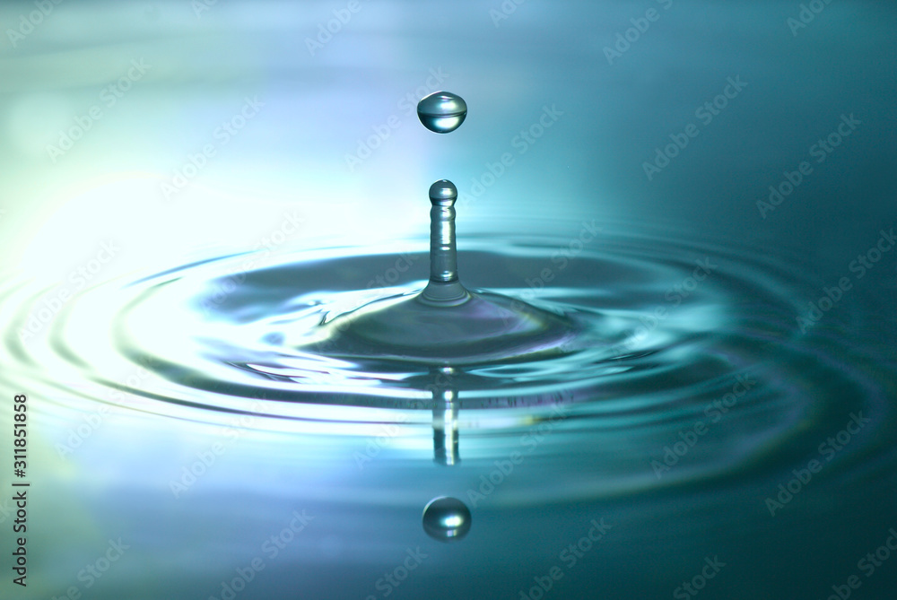 close up of a waterdrop splashing into metallic blue reflecting water close up of a waterdrop splashing into metallic blue reflecting water