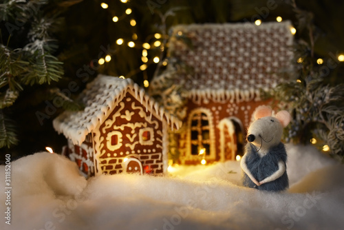 Gingerbread houses among winter magical scenery and 2020 white rat symbol. Sparkling lights in the background. Magical festive winter setting scenery.