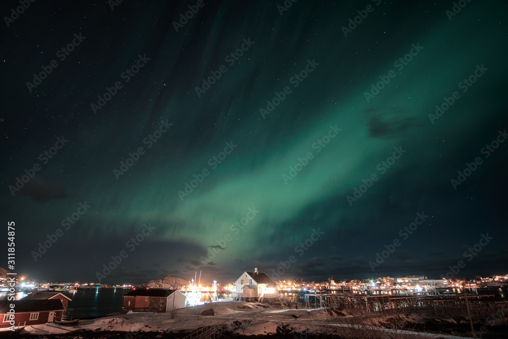 Northern lights, Aurora borealis over scandinavian village on coastline at Lofoten Islands