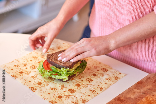 Woman hands wrapping a healthy sandwich in beeswax food wrap photo