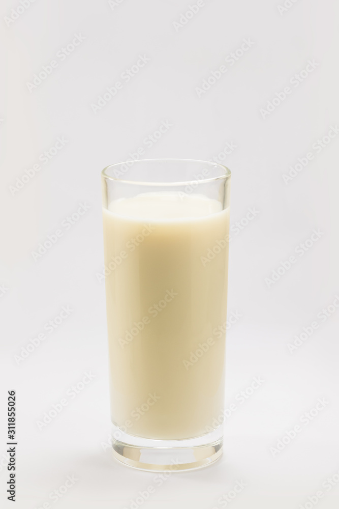 A cup of soy milk stands alone on a pale yellow background. A cup of soy milk stands alone on a pale yellow background.