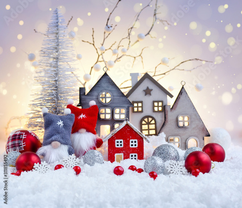 Christmas composition with gnomes, huts and festive decorations on the snow. Christmas or New Year greeting card.