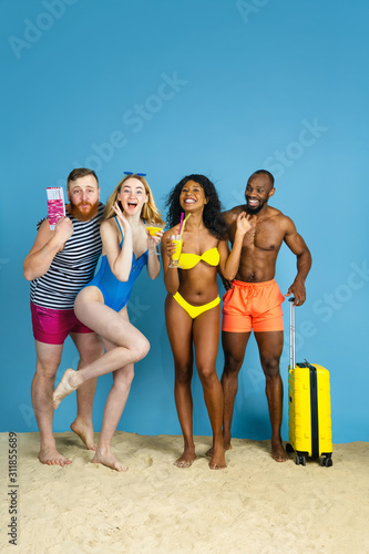 Best team for rest. Happy young friends resting and having fun on blue studio background. Concept of human emotions, facial expression, summer holidays or weekend. Chill, summertime, sea, ocean.