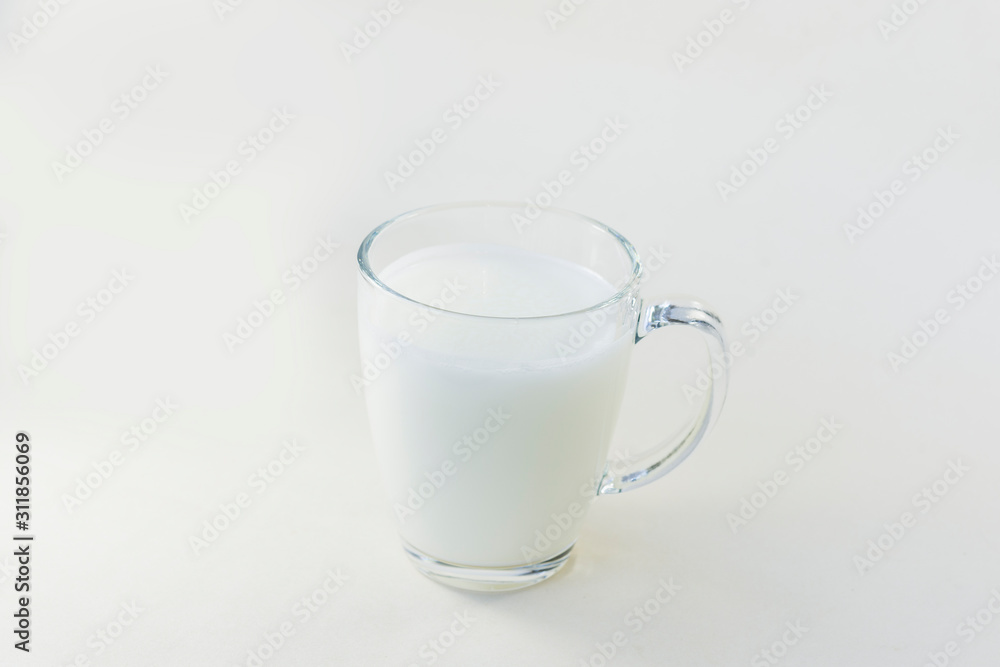 A cup of soy milk stands alone on a pale yellow background. A cup of soy milk stands alone on a pale yellow background.