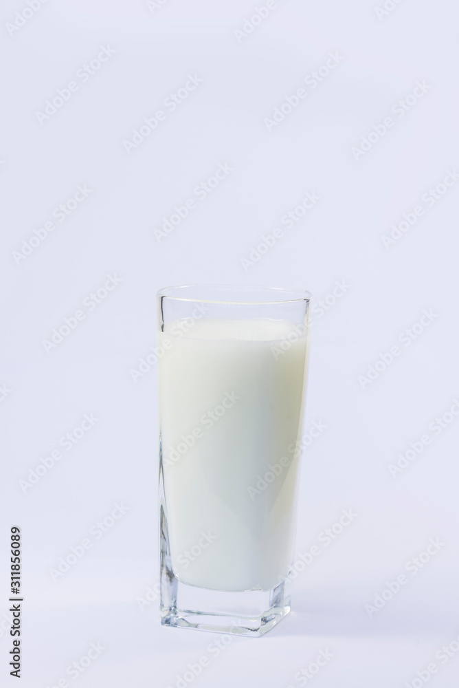 A cup of soy milk stands alone on a pale yellow background. A cup of soy milk stands alone on a pale yellow background.