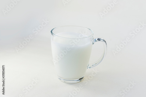 A cup of soy milk stands alone on a pale yellow background.