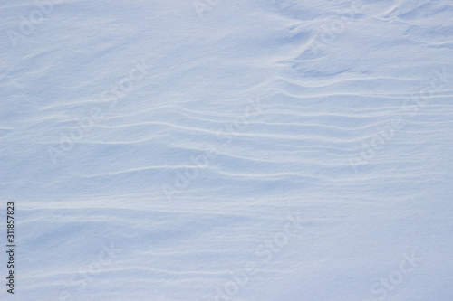 Natural winter background with snow drifts. Background of fresh snow texture in blue tones. High angle view of snow texture, background with copy space.