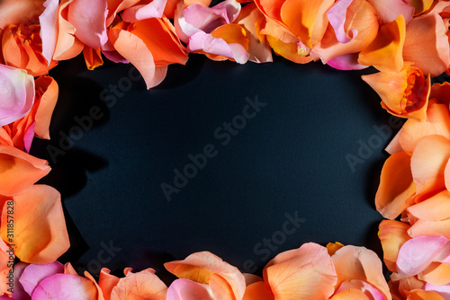 There are different colors (orange, pink) rose petals around the black background. Happy a Women's Day