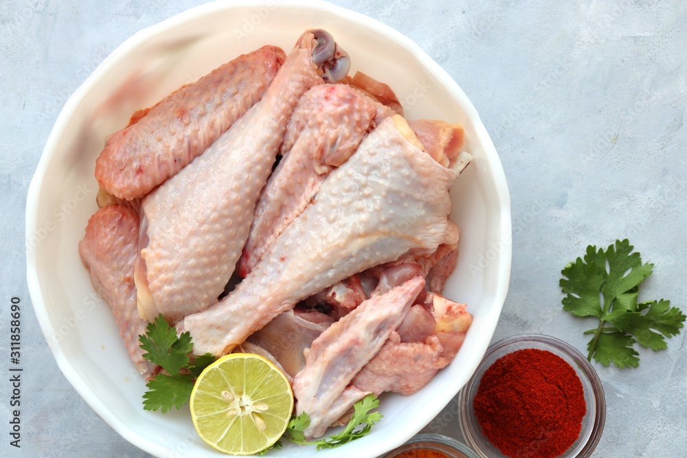 Clean and Raw Free range or country chicken carved in parts in a bowl with Indian spices and cooking ingredients. Along with copy space Clean and Raw Free range or country chicken carved in parts in a bowl with Indian spices and cooking ingredients. Along with copy space