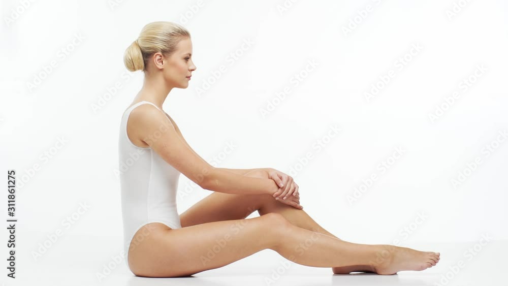 Young, beautiful, fit and natural blond woman in white swimsuit applying moisturizing cream. Massage, skin care, cellulite removal, sport and weight loss. Young, beautiful, fit and natural blond woman in white swimsuit applying moisturizing cream. Massage, skin care, cellulite removal, sport and weight loss.