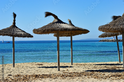 Wooden umbrellas on the empty sandy beach on Mallorca Islands in Spain