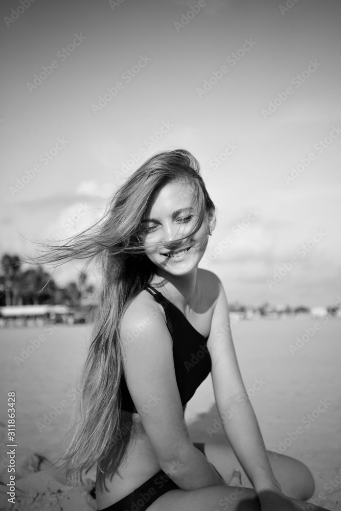 A young blonde laughs in beach, in black and white
