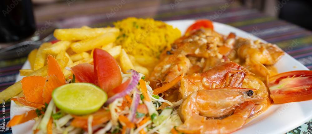 Delicious dish on restaurant table. Closeup plate of yummy dish with shrimps and french fries placed on ornamental table in cafe