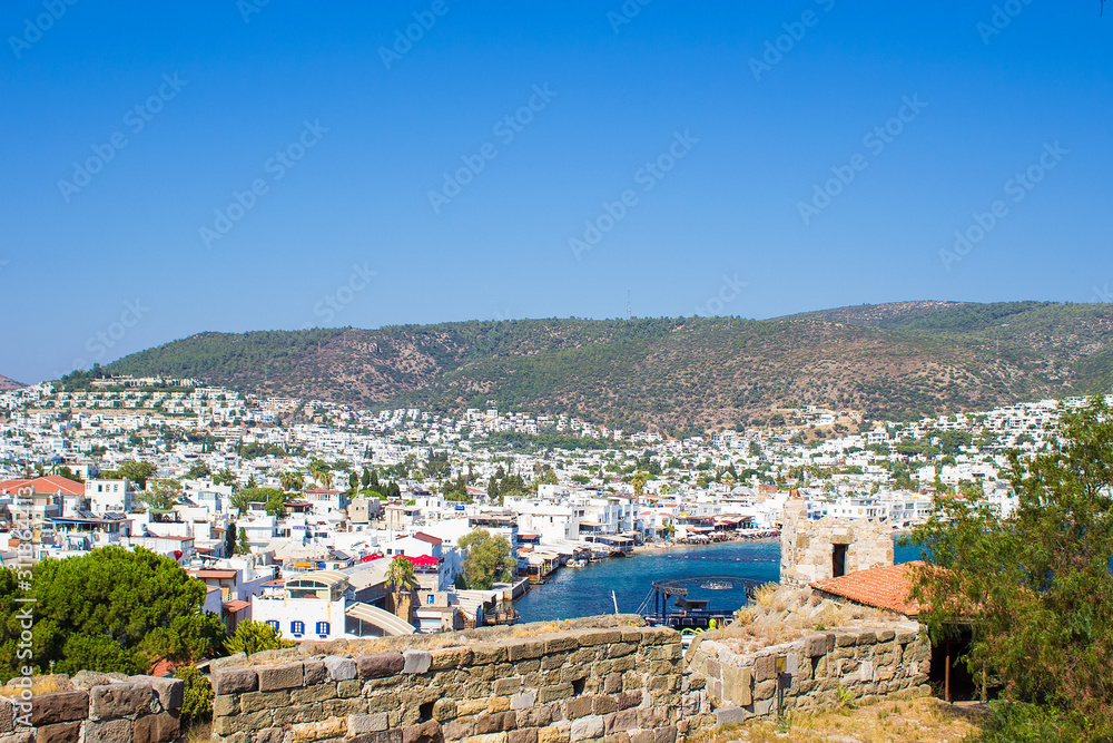 Panoramic view from the walls of  Bodrum castle (also known as St Peter Castle) in Bodrum. Famous white cubic buildings, blue Aegean sea and green nature on the background, Mugla, Turkey.