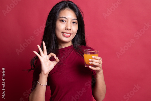 Young Asian woman drink orange juice show OK sign. © halfbottle
