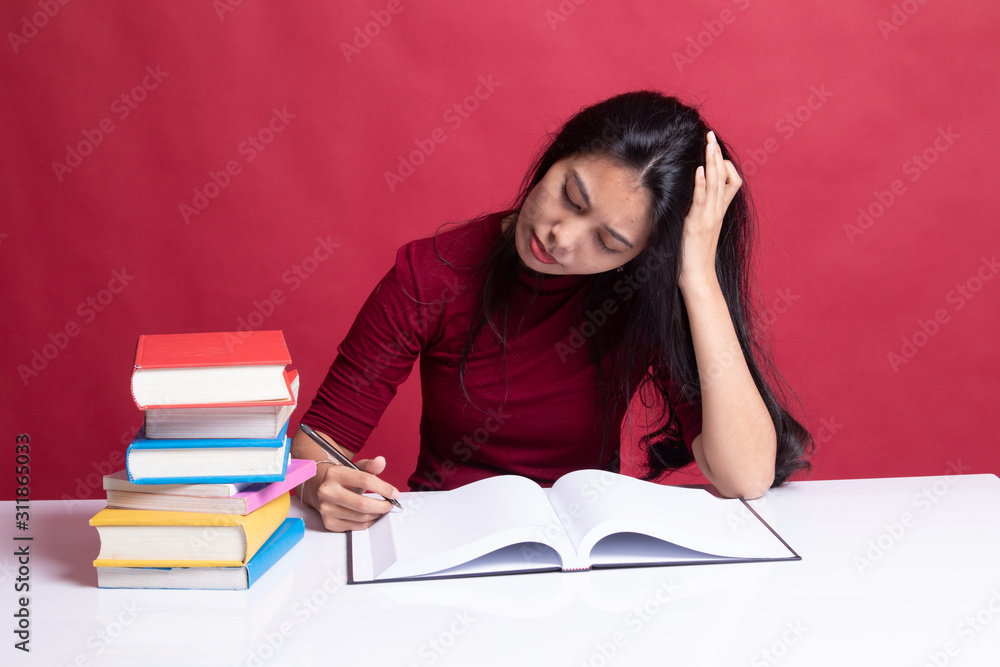 Exhausted Young Asian woman read a book with books on table. Exhausted Young Asian woman read a book with books on table.