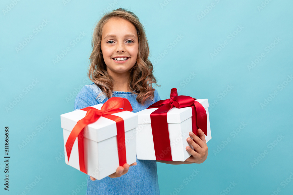 Caucasian child holds many white boxes with gifts and rejoices, portrait isolated on blue background Caucasian child holds many white boxes with gifts and rejoices, portrait isolated on blue background