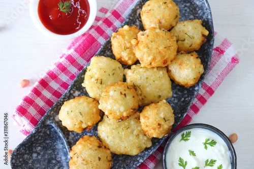 Sabudana vada or Sago fried fitters served with Curd or yogurt and ketchup over white wooden background, popular fasting recipe from India or mostly eaten during Fasting