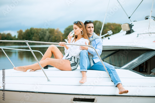 Lovers spending happy time on a yacht at sea. Luxury honeymood on a seaboat. Vacation, travel, sea, friendship and people concept. Smiling couple sitting and talking on yacht deck © Air_Lady