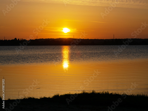landscape with sunset in the background, lake sand and grass in the foreground
