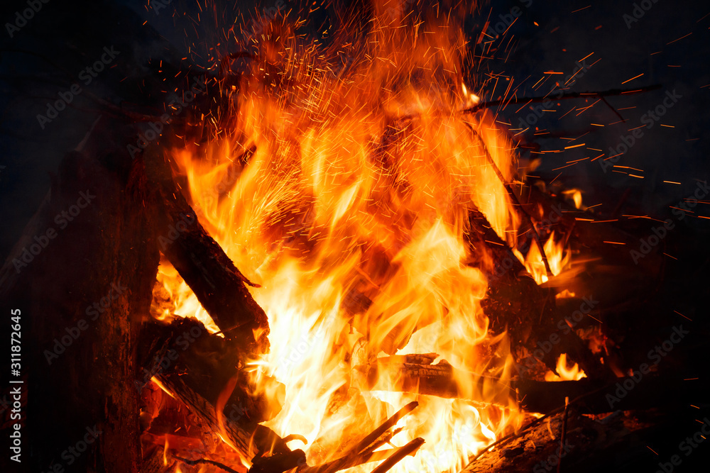 Colorful flame and sparks from a bonfire on a dark background