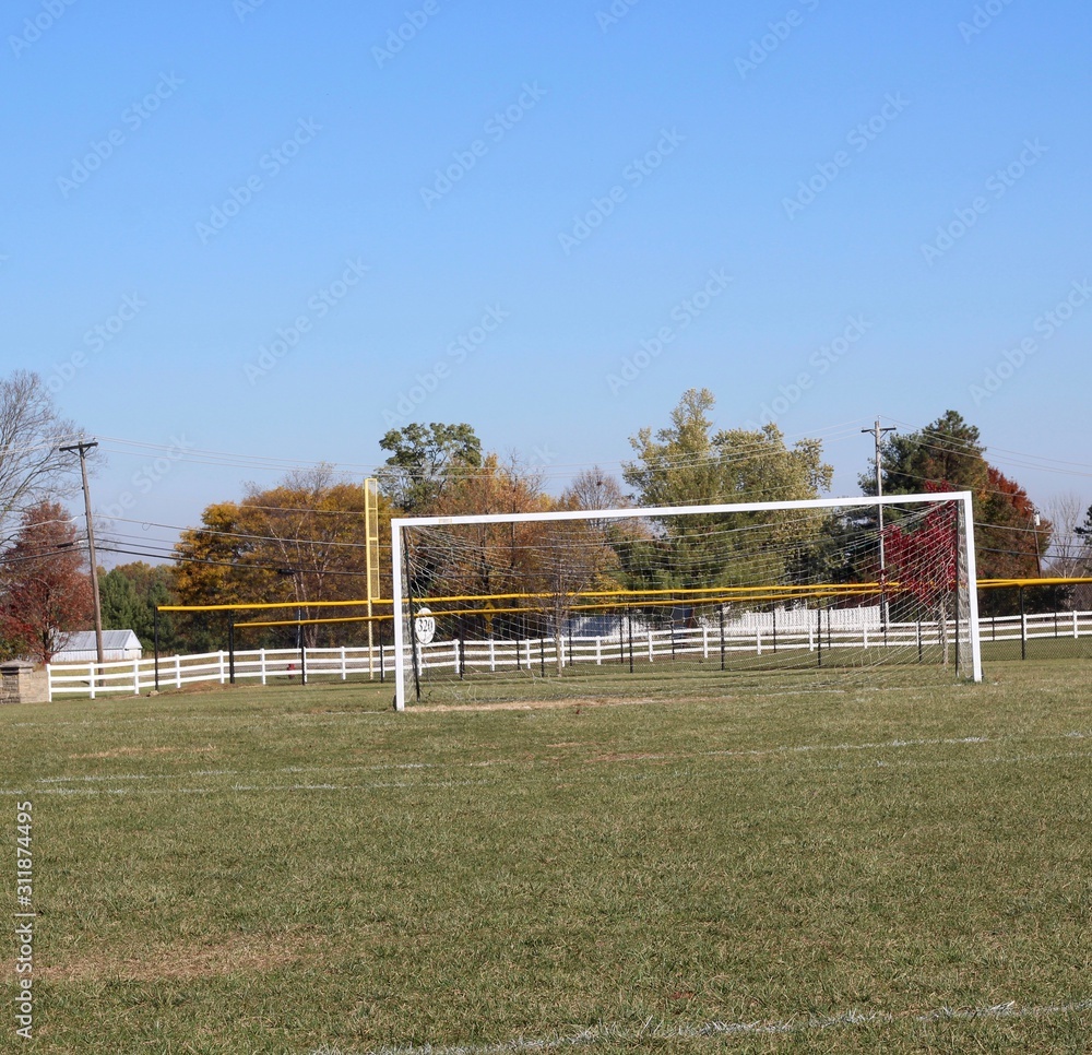 A view in front of the white soccer goal net in the field.