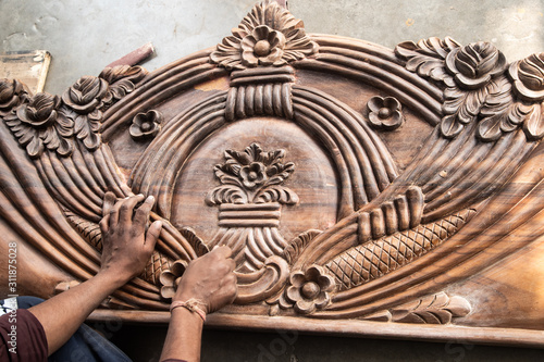 beautiful carved woodwork in an Indian street workshop. The hands of an Indian carpenter polishing the carved wooden headboard.