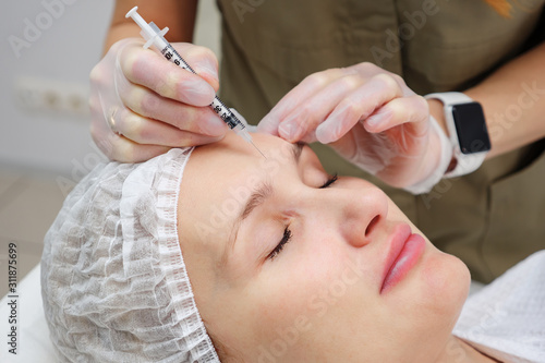 beauty clinic employee injects filler to fill deep and small wrinkles on woman face