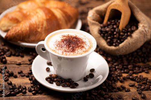 A cup of cappuccino with coffee bean as background.