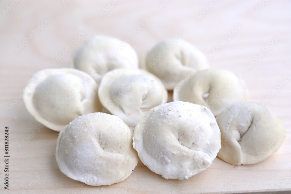 Several pieces of dumplings in flour and in pepper on a wood board before cooking Several pieces of dumplings in flour and in pepper on a wood board before cooking