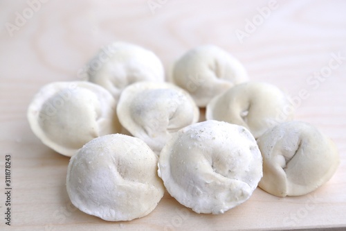 Several pieces of dumplings in flour and in pepper on a wood board before cooking