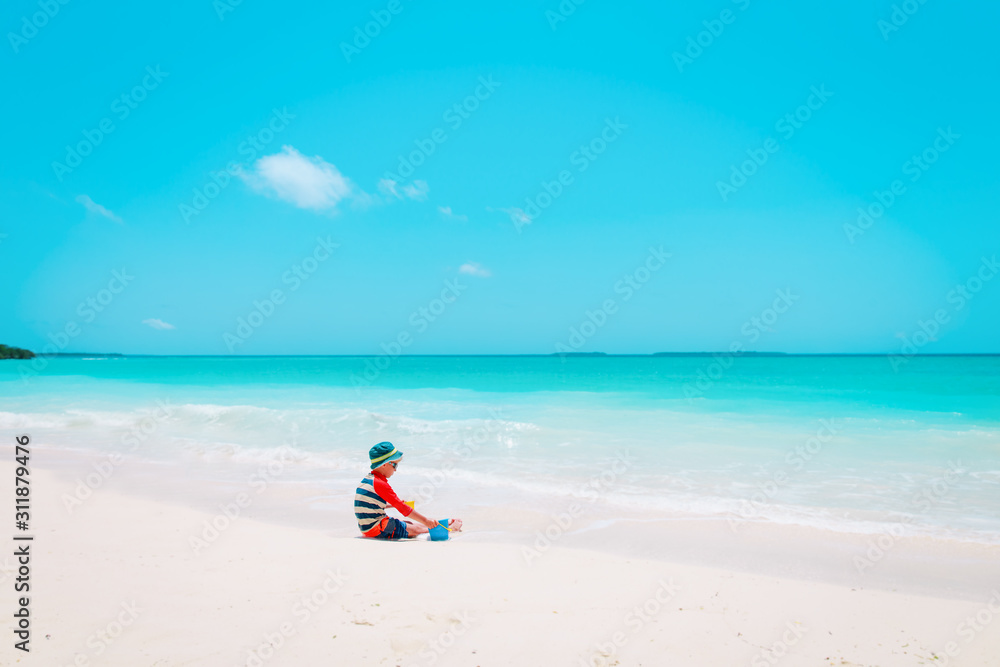 little boy play with toys and sand on beach