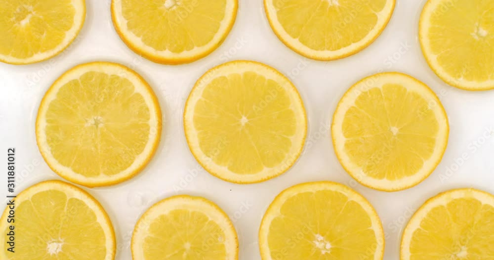 Top view: on a white background, a many fresh orange is lying in the water, water drops are falling from above and splashes are falling in slow motion in all directions Top view: on a white background, a many fresh orange is lying in the water, water drops are falling from above and splashes are falling in slow motion in all directions