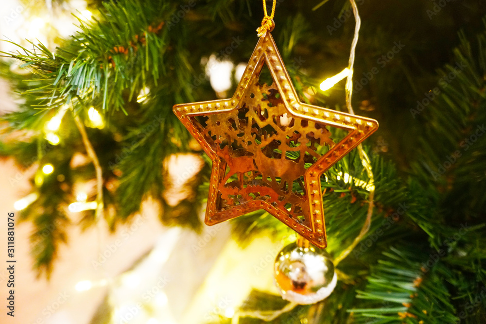Golden brass metal stars  hanging on the branch of a Christmas tree, Christmas background with festive decoration, solf focus.