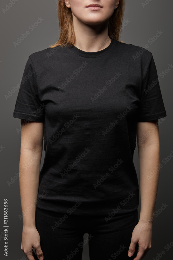 Obraz premium cropped view of woman in blank basic black t-shirt on black background