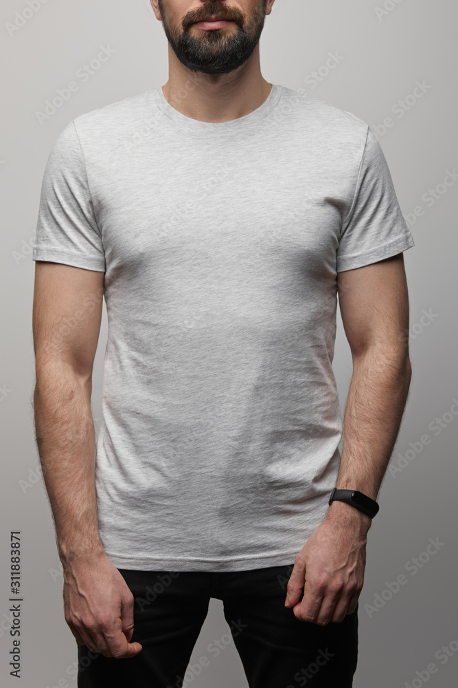 cropped view of bearded man in blank basic grey t-shirt isolated on grey cropped view of bearded man in blank basic grey t-shirt isolated on grey