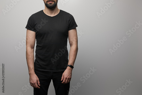 cropped view of bearded man in blank basic black t-shirt on grey background