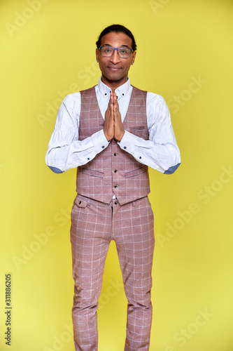 Vertical Portrait Young man with short-haired African American in a business suit on a yellow background. Standing and talking right in front of the camera.