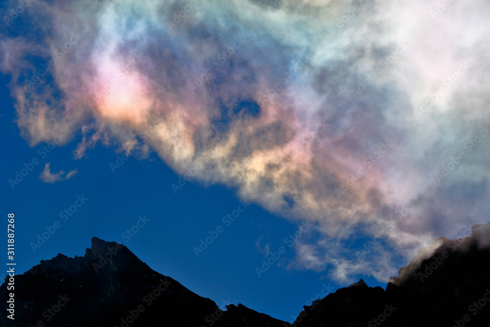 A natural phenomenon called iridescent clouds, in this case recorded in the morning with the light of the sun emerging from the rocks in the high Andean mountains.