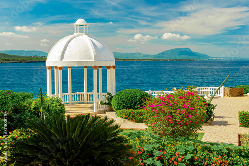 Beautiful white gazebo and tropical flower garden on Caribbean ocean background, summer mountain view , Sosua, Puerto Plata, Dominican Republic