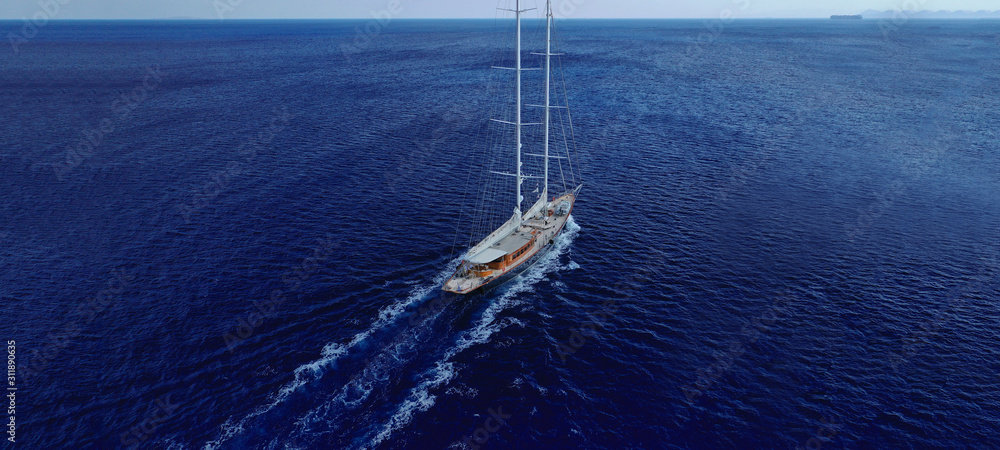 Fototapeta premium Aerial drone ultra wide photo of small wooden vessel cruising the Mediterranean deep blue sea