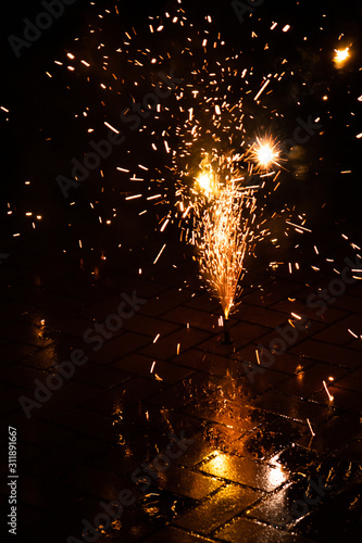 Funkensprühendes Feuerwerk einer Silvesterparty läutet das neue Jahr effektvoll ein und wünscht allen ein frohes neues Jahr mit Böllern, Knallern, Wunderkerzen und Bodenfeuerwerk mit Brandgefahr photo