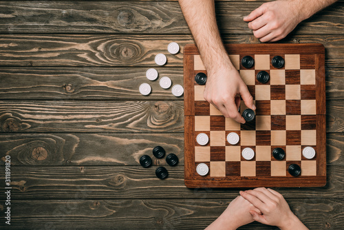 Top view of couple playing checkers on wooden background photo