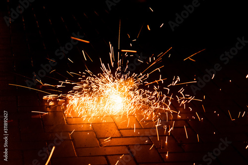 Funkensprühendes Feuerwerk einer Silvesterparty läutet das neue Jahr effektvoll ein und wünscht allen ein frohes neues Jahr mit Böllern, Knallern, Wunderkerzen und Bodenfeuerwerk mit Brandgefahr photo