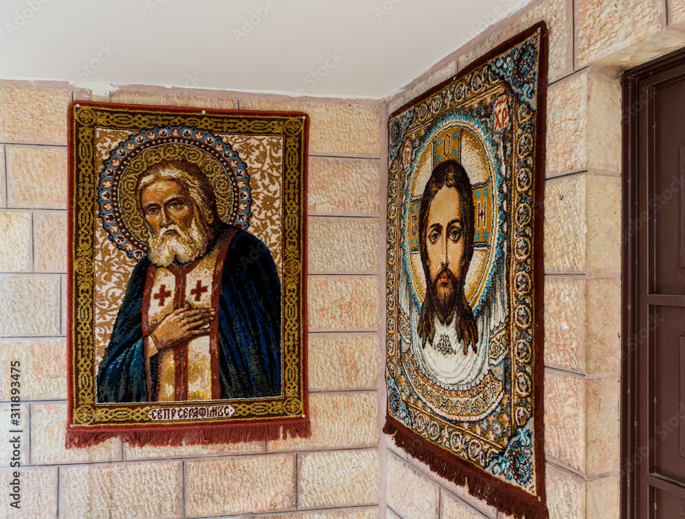 Carpets in the faces of Jesus and St. Seraphim hang on the wall of the St. Nicholas church in Bay Jala - a suburb of Bethlehem in Palestine